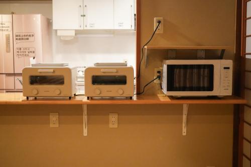 two microwaves and a microwave on a kitchen counter at Guesthouse Sign in Kyoto
