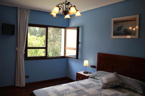 Dormitorio azul con cama y ventana en Sierra Pulide Apartamentos, en Salinas