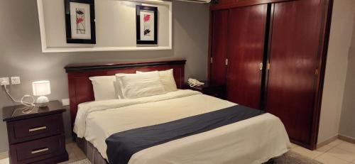 a bedroom with a large bed with a wooden headboard at Almeswari Suites in Al Baha