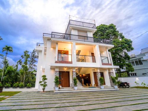 a white house with a balcony at Oasis Apartment with Pool in Vythiri in Vythiri