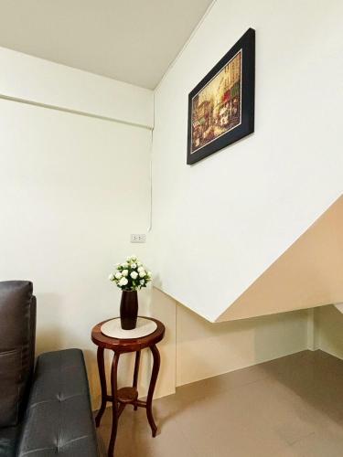 a living room with a couch and a table with flowers at Dee Tee homestay hatyai in Ban Kohong
