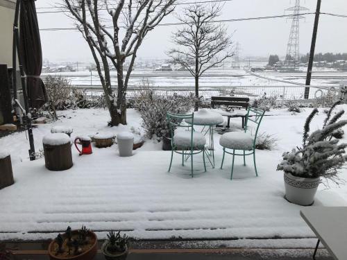 a patio with a table and chairs covered in snow at ヨーコのお宿 わくわく in Toyama