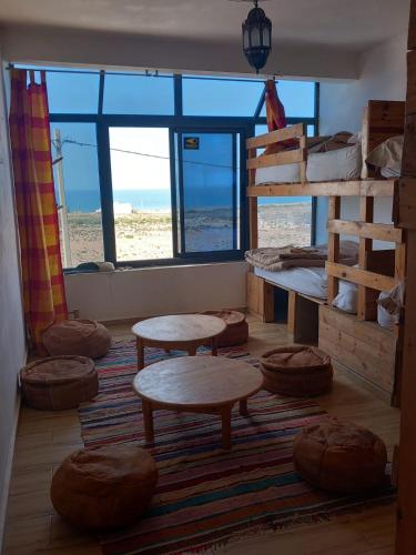 a room with bunk beds and tables and a beach at EL Faro Surfstay in Tamri