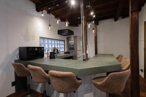 a kitchen with a counter with chairs around it at ナカノコミチ Nakanokomichi in Tokyo