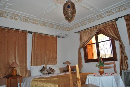 a bedroom with a bed and a window and a table at Riad Villa Midelt in Midelt