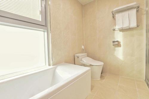 a bathroom with a tub and a toilet and a window at Berith Hotel in Sokcho