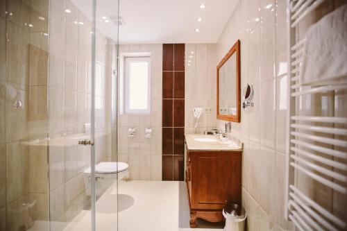 a bathroom with a toilet and a sink and a shower at Elixír Medical Wellness Hotel in Mórahalom