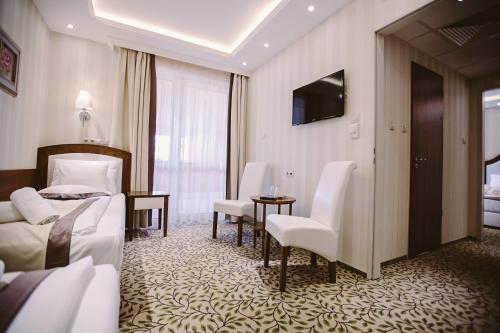a hotel room with two beds and a table and chairs at Elixír Medical Wellness Hotel in Mórahalom