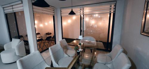 a living room with white chairs and a table at Tu Hogar con alberca en Ags, a 5 min de la feria in Aguascalientes