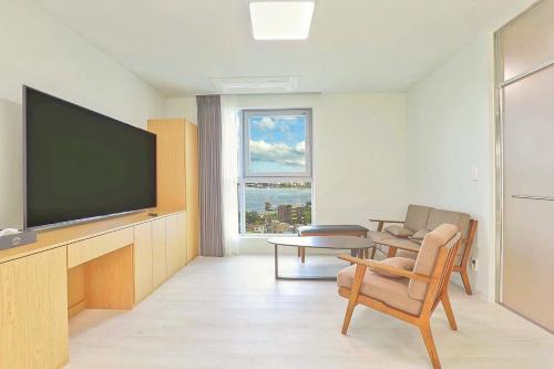a living room with a flat screen tv and a chair at Berith Hotel in Sokcho
