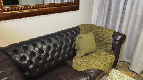 a brown leather couch with a green pillow on it at Border Close Guesthouse in Upington