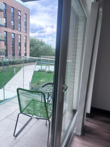 a green chair sitting on a balcony next to a sliding glass door at The Ivy Abode 2 bedroom Apartment in Harlow