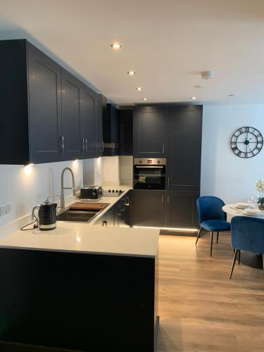 a kitchen with black cabinets and a table with a blue chair at The Sunrise Den-Lovely 2 bedroom apartmentParking in Harlow