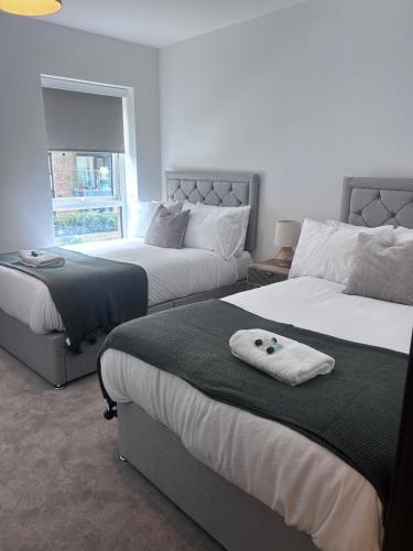 a bedroom with two beds and a window at The Ivy Abode 2 bedroom Apartment in Harlow