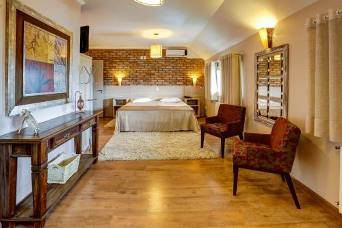 1 dormitorio con 1 cama, 2 sillas y mesa en Di Capri Hotel en Farroupilha