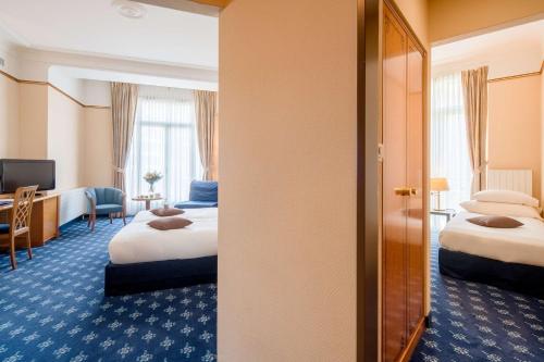 a hotel room with two beds and a desk at Hotel Mirabeau, BW Signature Collection, Lausanne in Lausanne