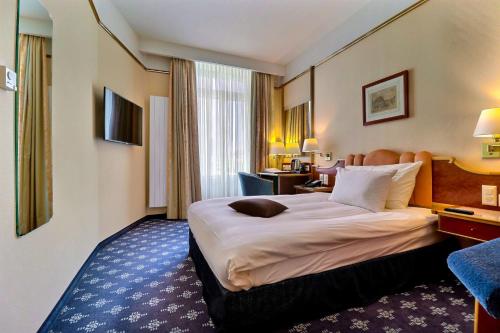 a hotel room with a large bed and a desk at Hotel Mirabeau, BW Signature Collection, Lausanne in Lausanne