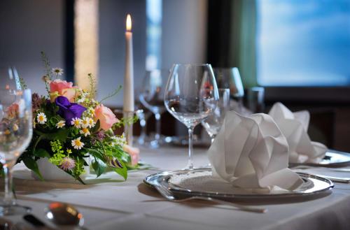 a table with a candle and flowers and wine glasses at Best Western Hotel Das Donners in Cuxhaven