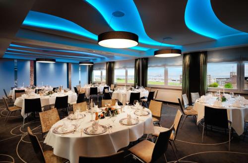 a banquet room with tables and chairs with white tablecloths at Best Western Hotel Das Donners in Cuxhaven