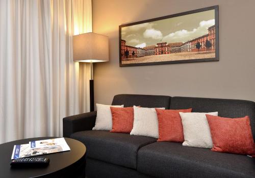 a living room with a gray couch with red and white pillows at Best Western Plus Delta Park Hotel in Mannheim