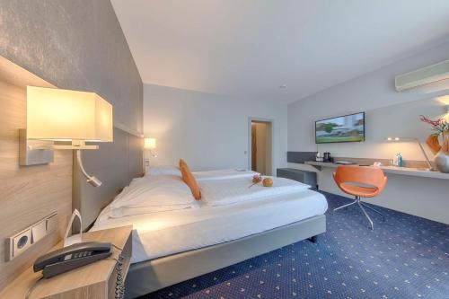 a hotel room with a large bed and a desk at Best Western Plus Hotel Steinsgarten in Gießen