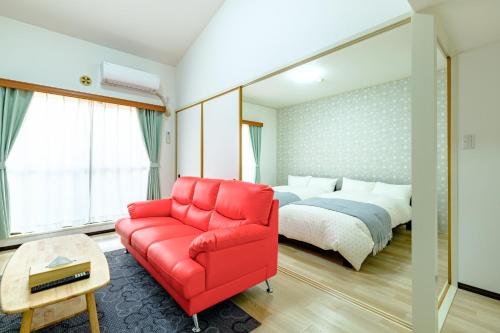 a bedroom with a red couch and a bed at さくらハウス - Sakura house - 広々快適 最大6名滞在可 in Tokyo