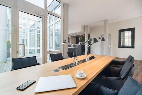 an office with a wooden table with a laptop on it at Best Western Plus Atrium Hotel in Ulm