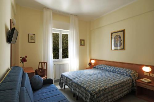 a bedroom with a bed and a blue couch at Hotel Tritone in Laigueglia