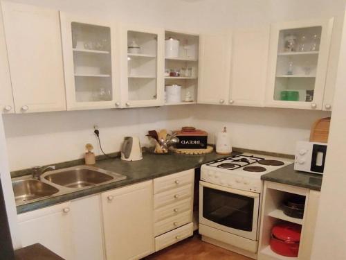 eine Küche mit weißen Schränken, einem Herd und einer Spüle in der Unterkunft Holiday Home Jaga - Three bedroom Holiday Home with swimming pool in Biograd na Moru