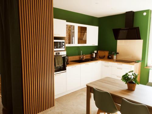 une cuisine avec des armoires blanches et des murs verts dans l'établissement L'appart d'Arches - 85m2 2 chambres centre ville, à Charleville-Mézières