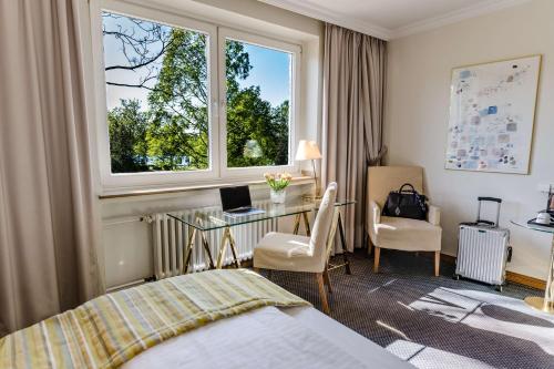 a hotel room with a bed and a desk and a window at Best Western Premier Seehotel Krautkrämer in Münster