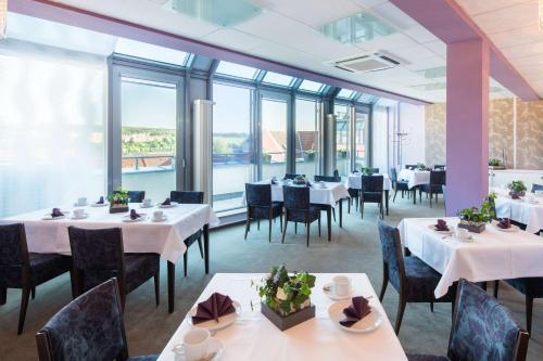 a restaurant with white tables and chairs and windows at Best Western Hotel Am Straßberger Tor in Plauen