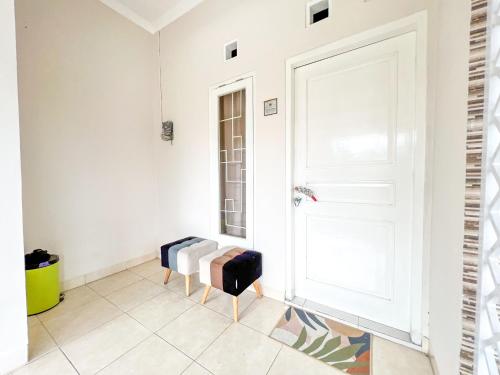 NgaglikGriya Lojajar Homestay Jogja的走廊设有白色门和两把椅子