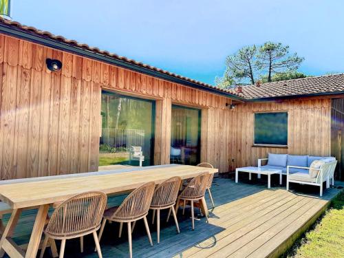 une terrasse en bois avec une table et des chaises dans l'établissement Villa bois sur la presqu'île du Cap Ferret, à Lège-Cap-Ferret