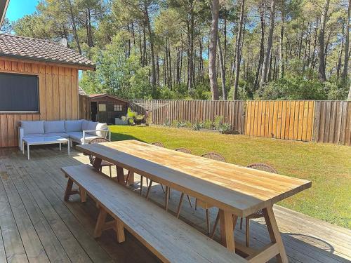 - une table de pique-nique en bois assise sur une terrasse dans une cour dans l'établissement Villa bois sur la presqu'île du Cap Ferret, à Lège-Cap-Ferret