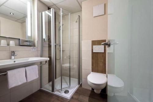 a bathroom with a shower and a toilet and a sink at Best Western Plus Hotel Willingen in Willingen