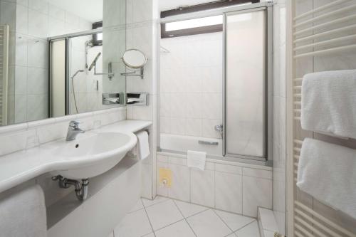 a white bathroom with a sink and a shower at Best Western Hotel Heide in Oldenburg