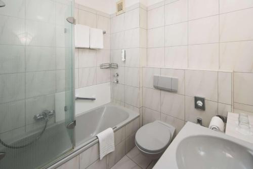 a bathroom with a toilet and a tub and a sink at Best Western Hotel Heide in Oldenburg