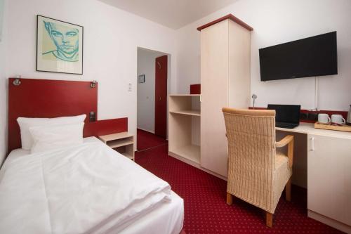 a hotel room with a bed and a desk with a computer at Best Western Hotel Heide in Oldenburg