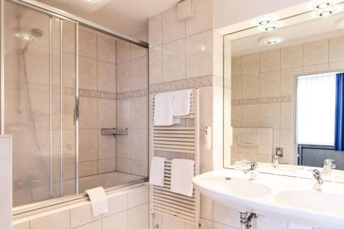 a bathroom with a shower and a sink and a tub at Best Western Hotel Heide in Oldenburg