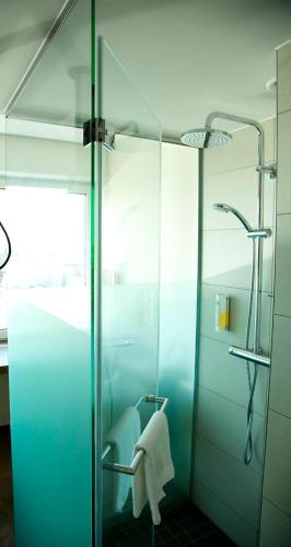 a bathroom with a glass shower with a towel at Best Western Plus Hotel Bremerhaven in Bremerhaven