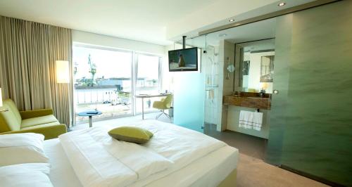 a bedroom with a large white bed and a bathroom at Best Western Plus Hotel Bremerhaven in Bremerhaven