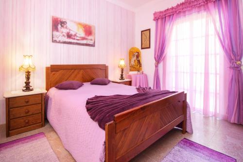 a bedroom with a large bed and purple curtains at Vivenda Costa in Odeceixe