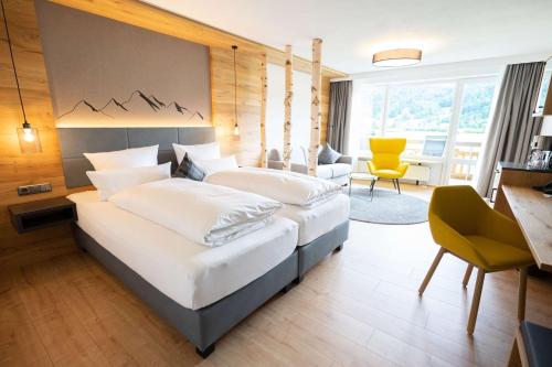 a bedroom with two beds and a desk and a chair at Best Western Plus Hotel Alpenhof in Oberstdorf
