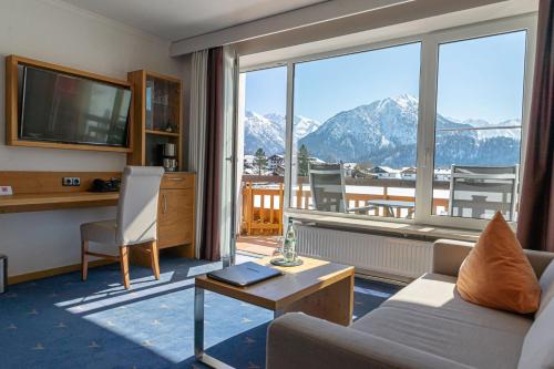 a living room with a couch and a large window at Best Western Plus Hotel Alpenhof in Oberstdorf