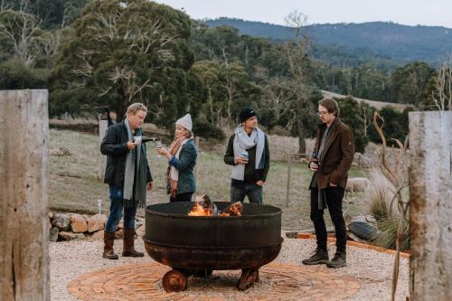 a group of people standing around a fire pit at Fellcroft Farmstay in Cobaw