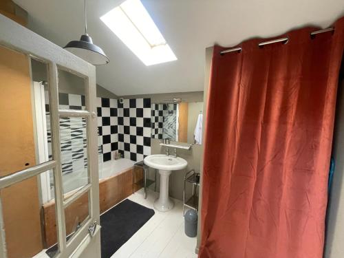 La salle de bains est pourvue d'un rideau de douche rouge et d'un lavabo. dans l'établissement LOFT rive droite, à Saintes