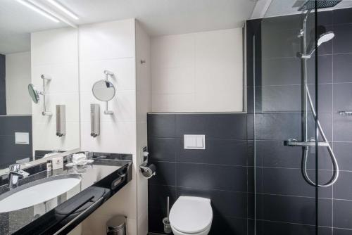 a bathroom with a shower and a toilet and a sink at Best Western Plus Plaza Hotel Darmstadt in Darmstadt