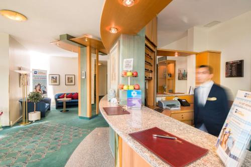 a man standing at a counter in a room at PLAZA INN Blankenburg Ditzingen, Sure Hotel Collection in Ditzingen