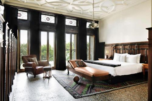 a bedroom with a bed and a chair and windows at Chicago Athletic Association, part of Hyatt in Chicago